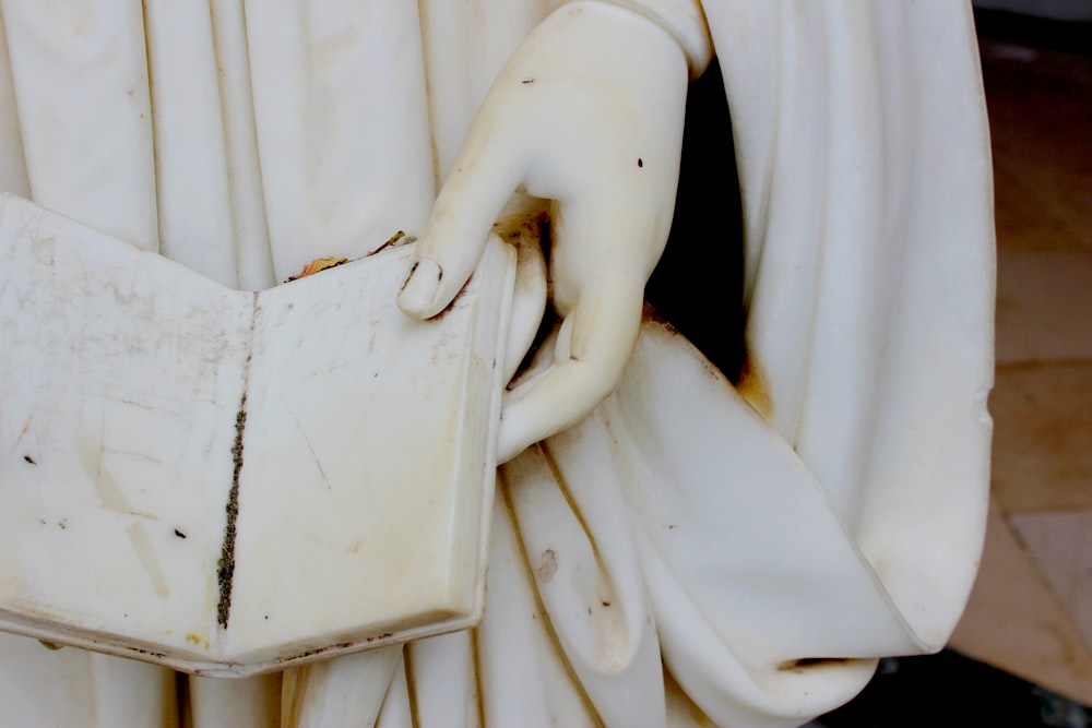 a close up of a statue holding a book