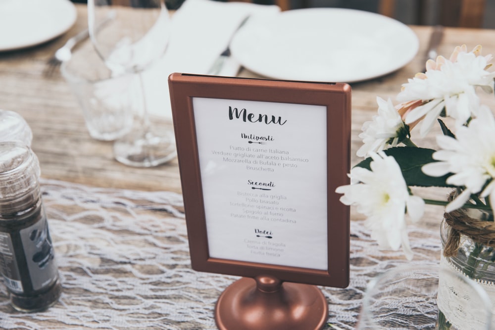 Tafel mit Menüdruck und braunem Rahmen auf dem Tisch