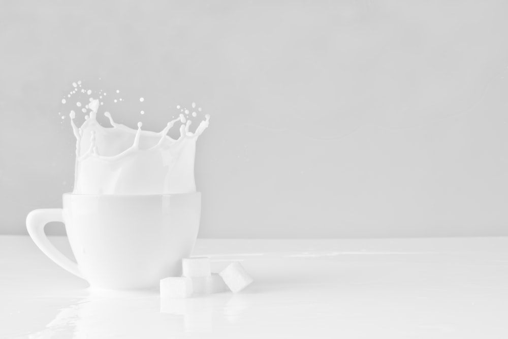 blocco di zucchero caduto su una tazza bianca con latte