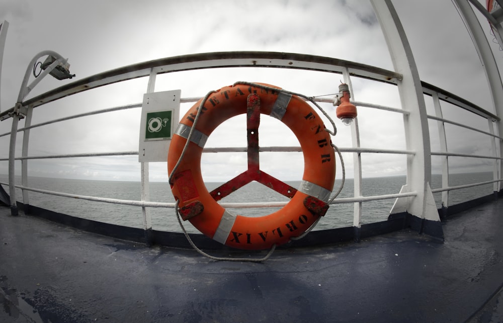 orange lifebuoy hanging on boat fence