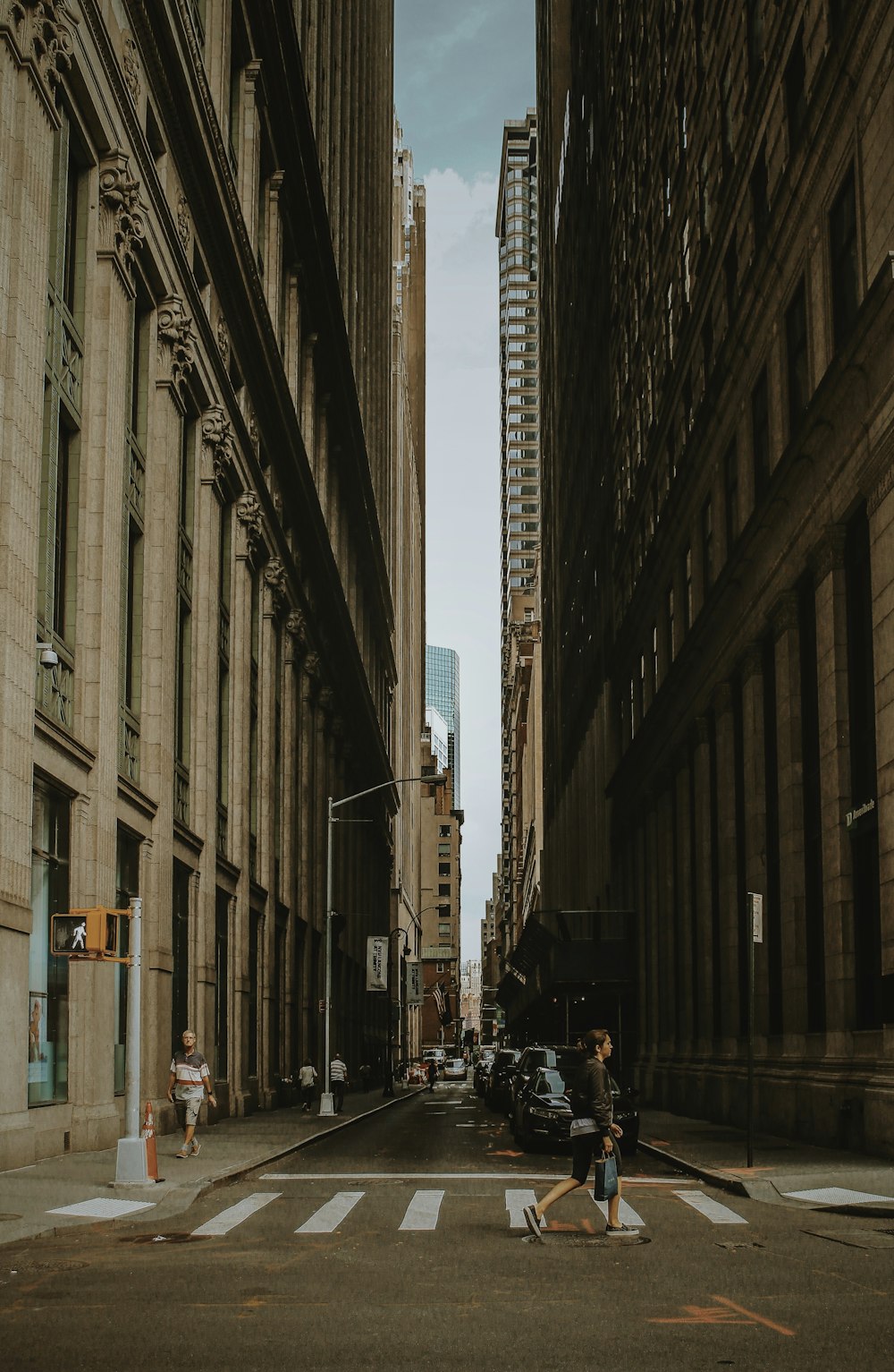 woman walking on street between building during daytime