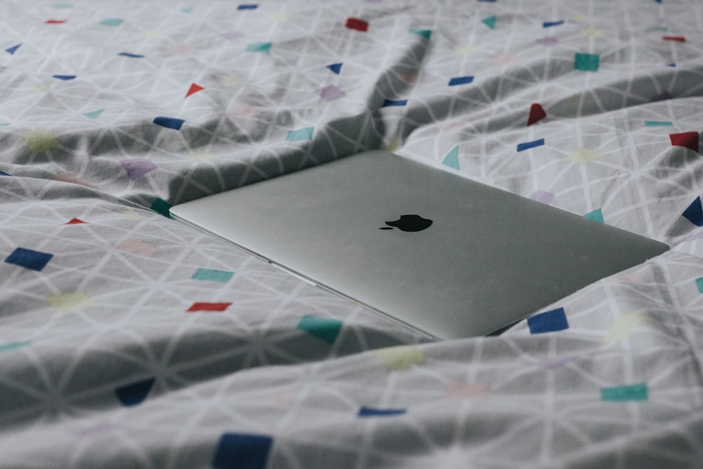 MacBook plateado sobre textil de colores variados