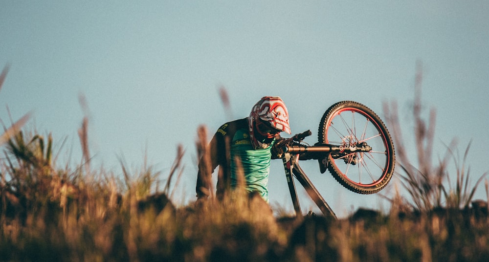 man carrying black mountain bike uphill