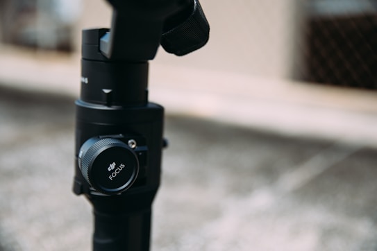 A close-up of a camera or lens component featuring the DJI Focus dial prominently. The background is blurred, highlighting the focus adjustment tool on the device.