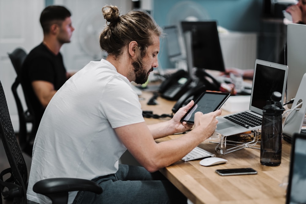 man holding turned-on iPad in front of turned-off MacBook Air