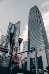 A panoramic view of a modern Sharjah skyline with cranes and construction workers actively building a new structure.