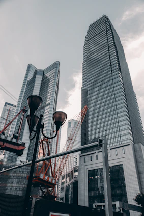 A panoramic view of a modern Sharjah skyline with cranes and construction workers actively building a new structure.