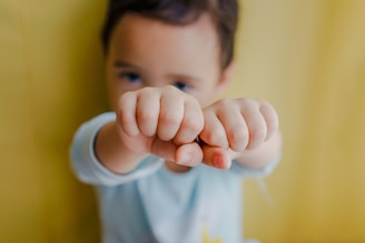 toddler boy wearing white shirt leaning back on brown wooden wall