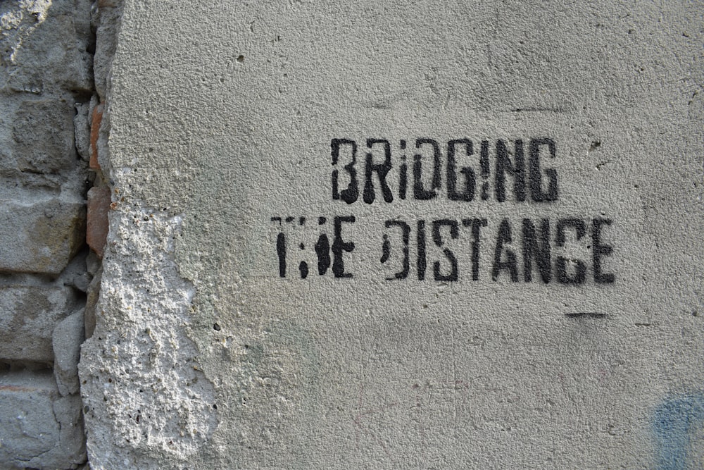 bridging the distance text on gray concrete surface close-up photography