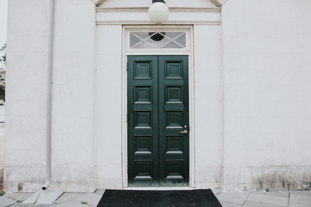 alfombra de puerta negra colocada cerca de la puerta de entrada negra