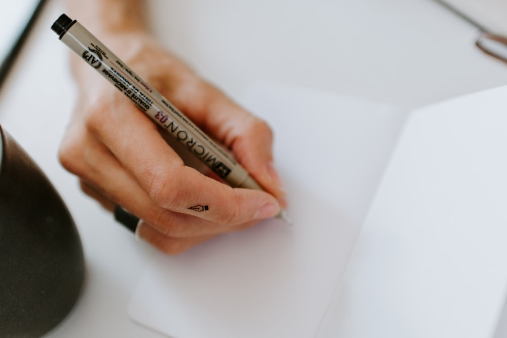 person using pen on white paper