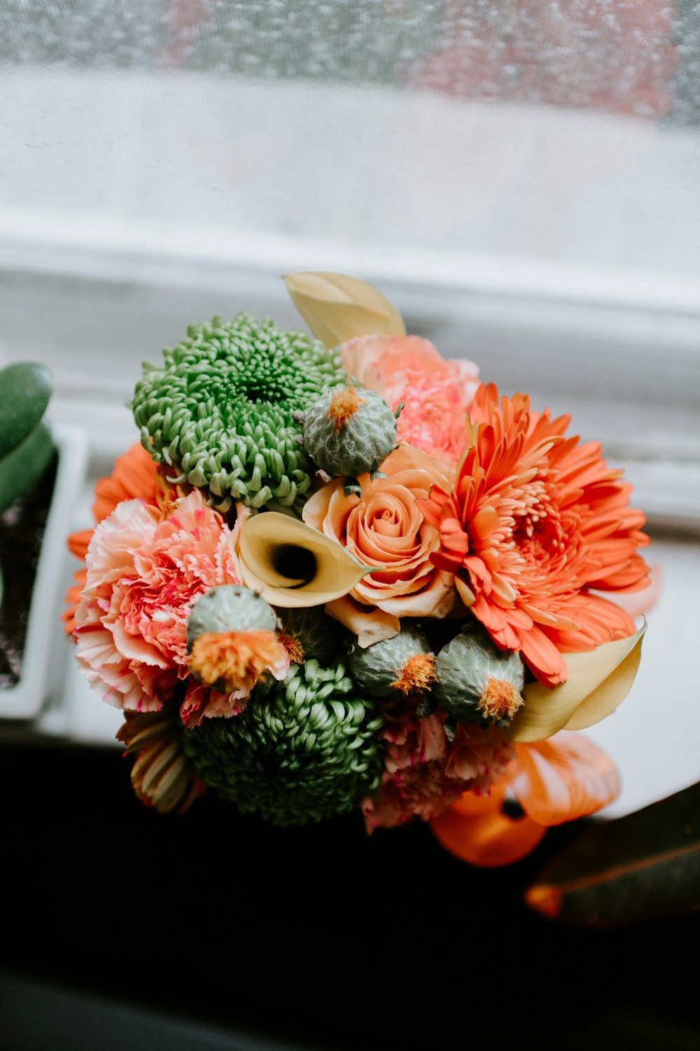 bouquet de flores artificiais amarelo, verde e bege na superfície branca