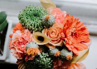 yellow, green, and beige artificial flower bouquet on white surface