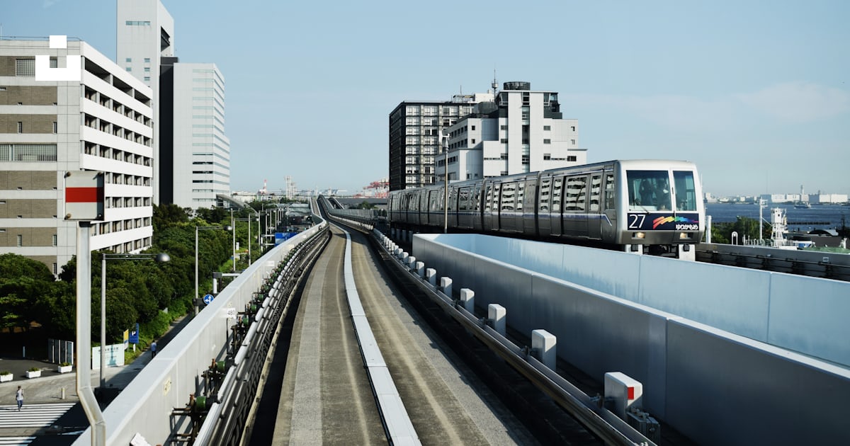 Grey train running through the railing near the white building photo ...