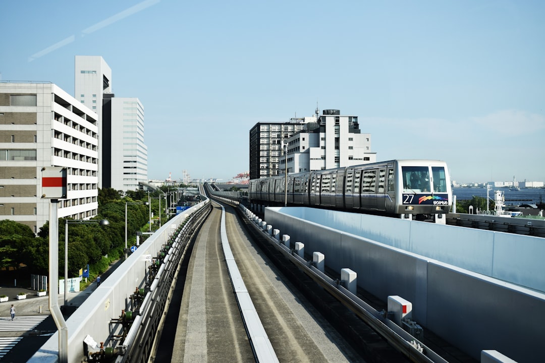 grey train running through the railing near the white building