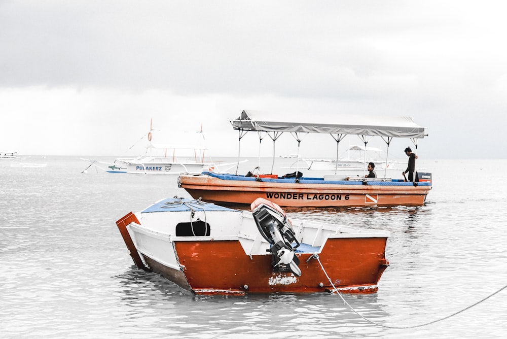 red and white motorboat on body of water under white sky at daytime