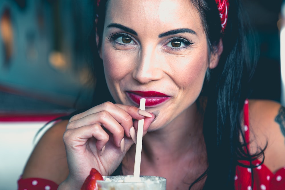 woman wearing red and white polka-dot top holding straw close-up photo