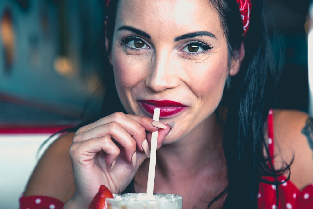 Femme portant un haut à pois rouge et blanc tenant une photo en gros plan de paille