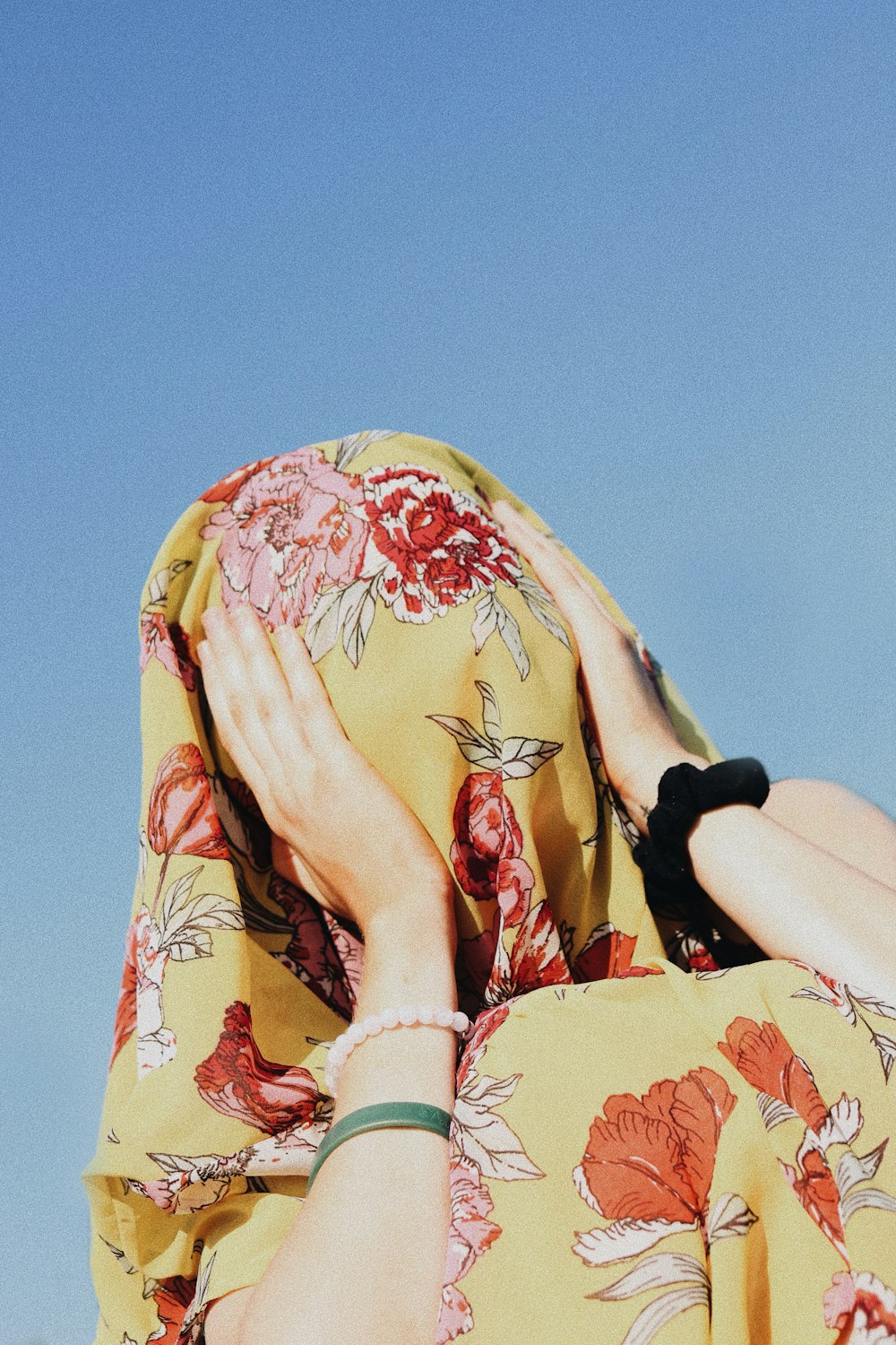 woman covering her face with yellow floral headdress