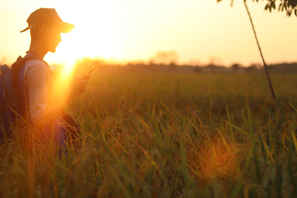 man walking on grass field while holding a smartphone