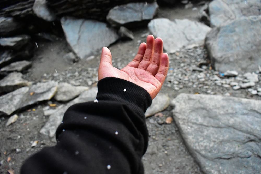a person's hand reaching out towards a rocky area