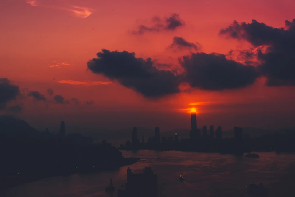 Breathtaking sunset over city skyline with tall buildings silhouetted against vibrant hues of orange