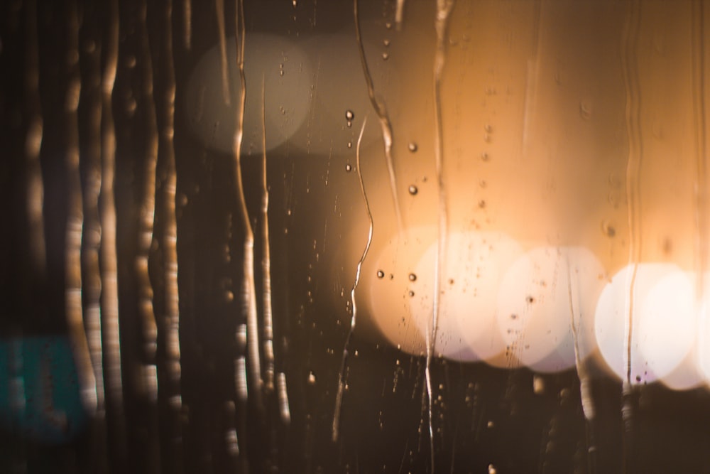 Regentropfen auf ein Fenster mit Lichtern im Hintergrund
