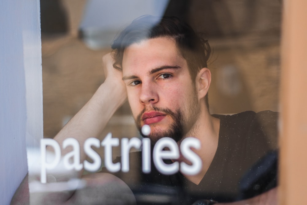 man leaning near clear glass window