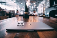 selective focus photography of white AirPods with charging case on silver MacBook on table