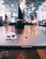 selective focus photography of white AirPods with charging case on silver MacBook on table