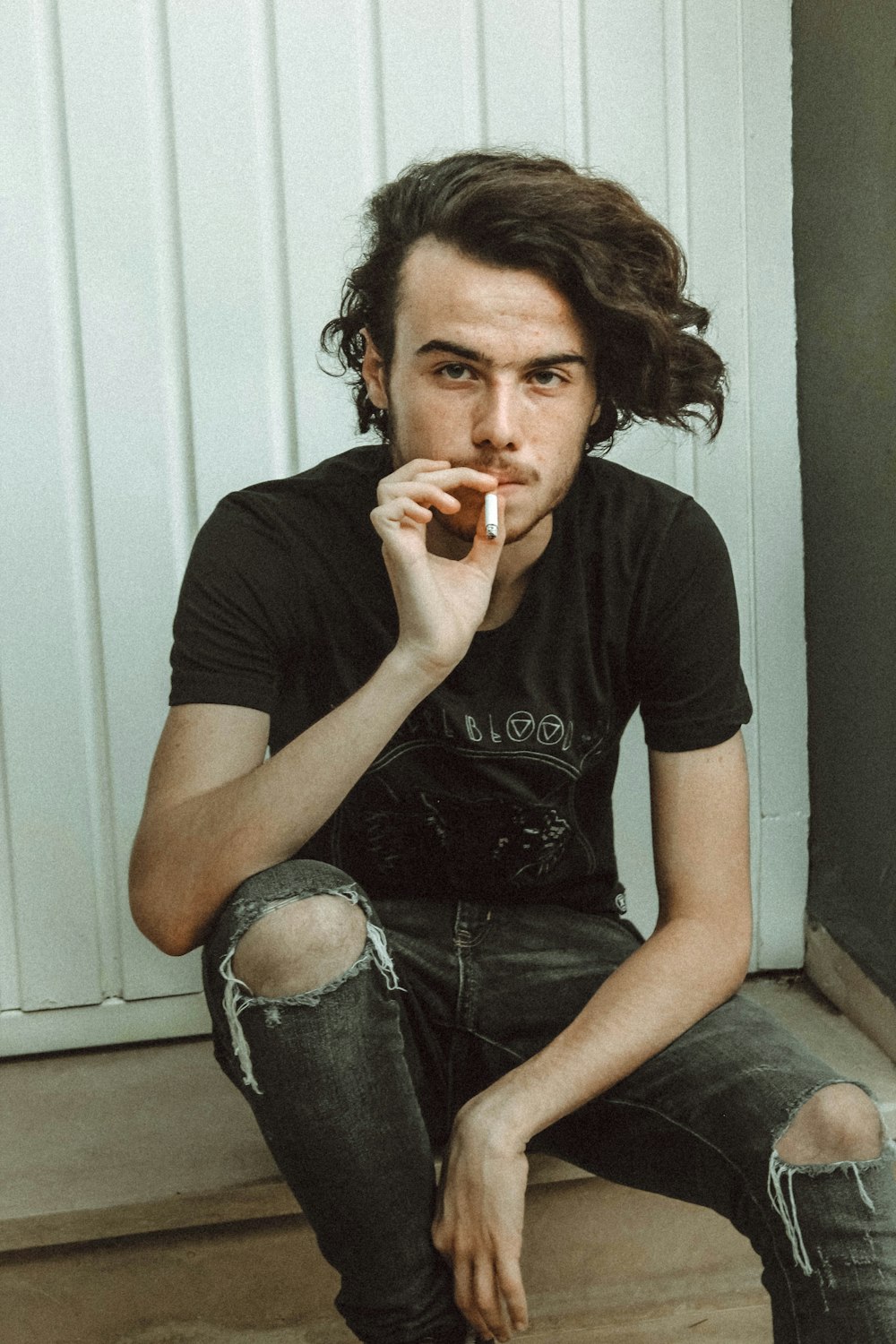 man holding cigarette near wall