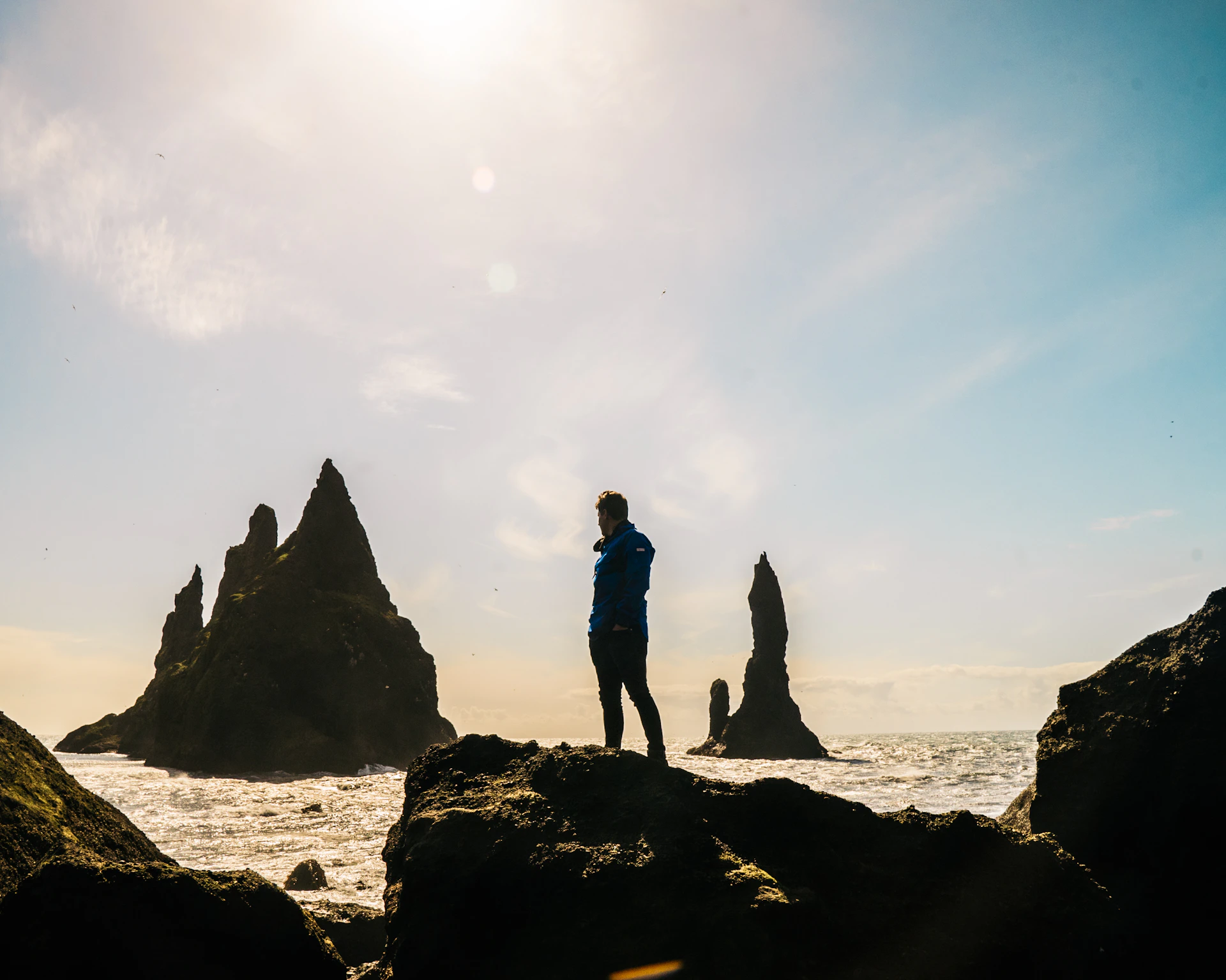 Close-up of a waterproof jacket with bold colors, hanging on a rocky seaside cliff under a clear blue sky.