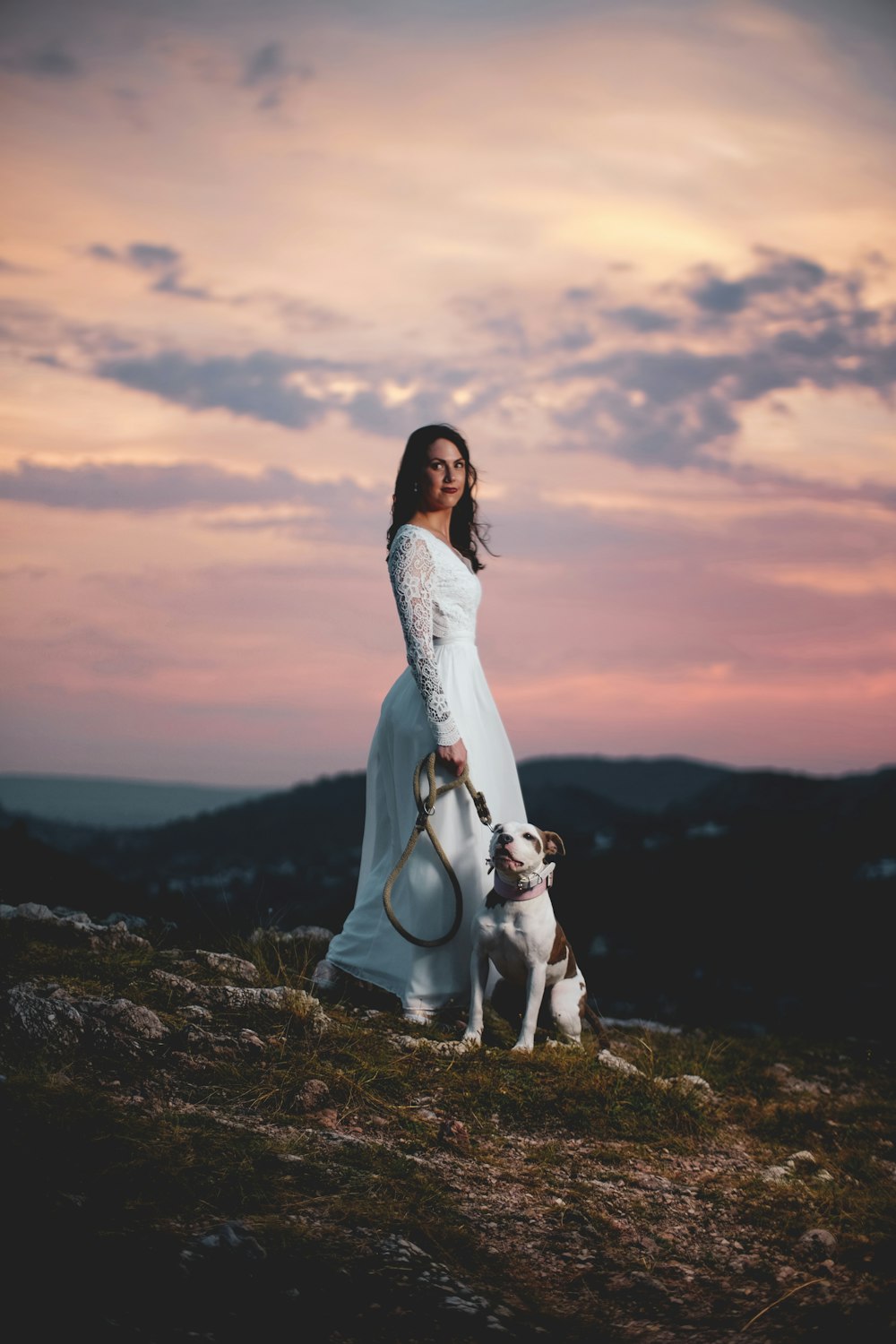 woman wearing white lace gown with dog sitting on the ground