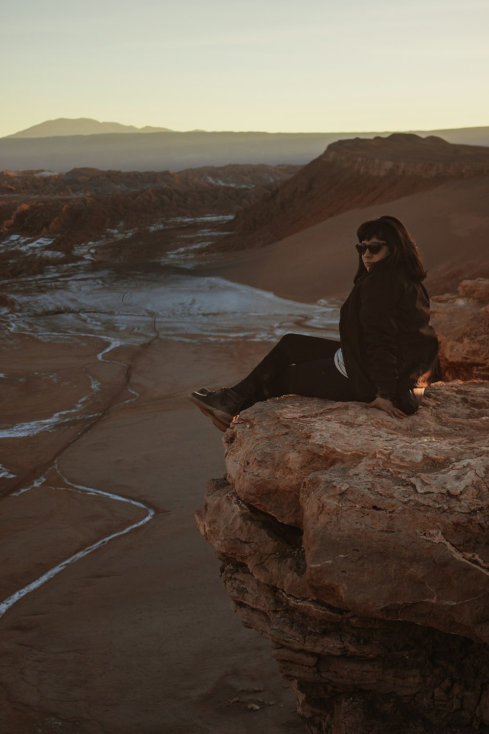 Mujer sentada en el borde de la montaña