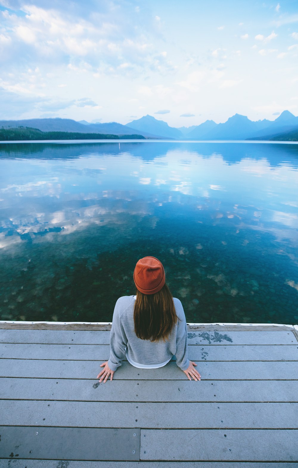woman sitting in front of calm body of water