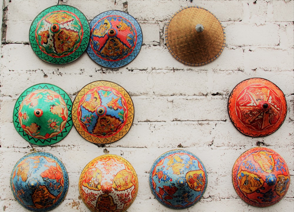 ten assorted-color floral straw hats on white surface