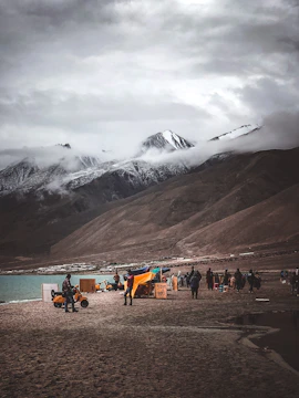 group of person beside mountain under cloudy sky