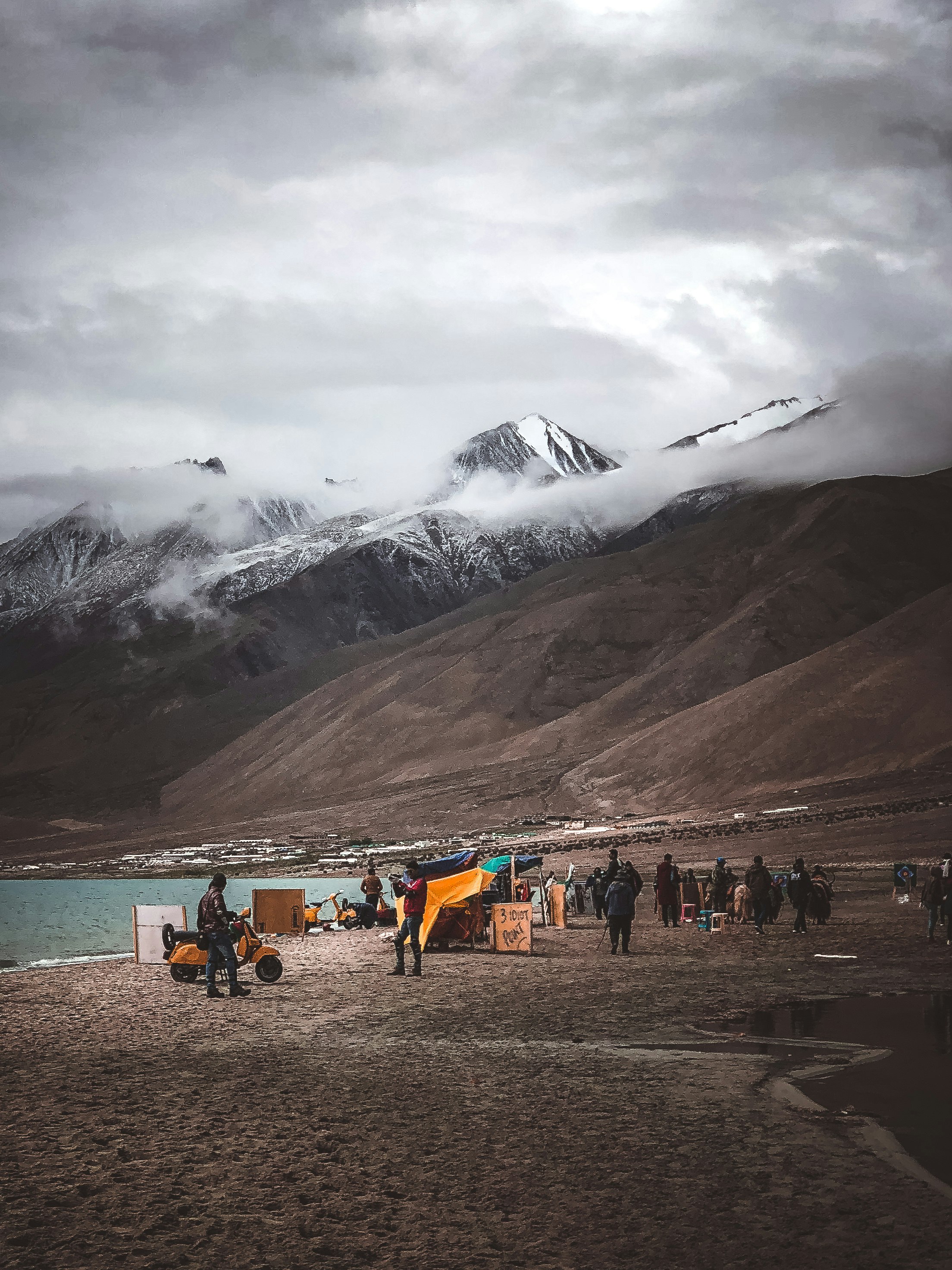 group of person beside mountain under cloudy sky