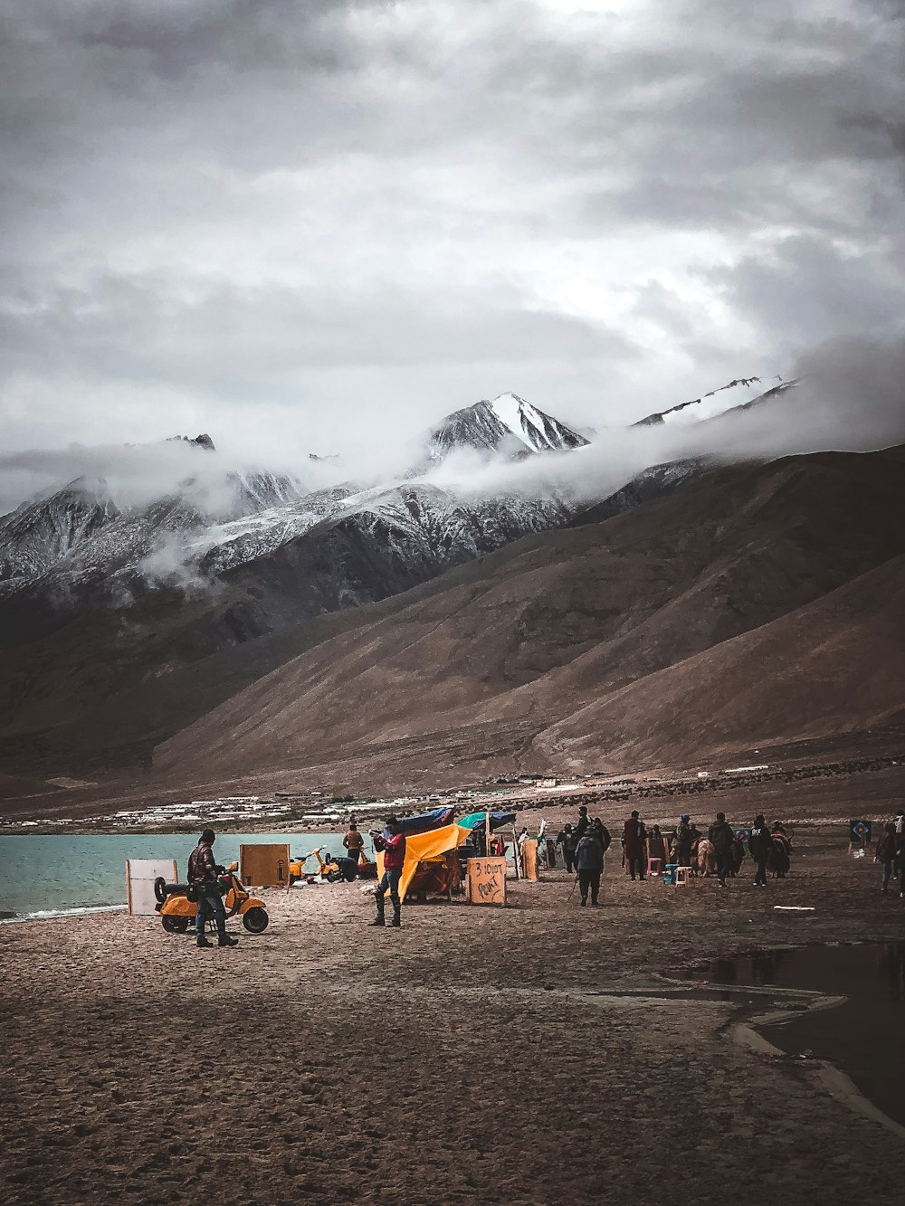 group of person beside mountain under cloudy sky