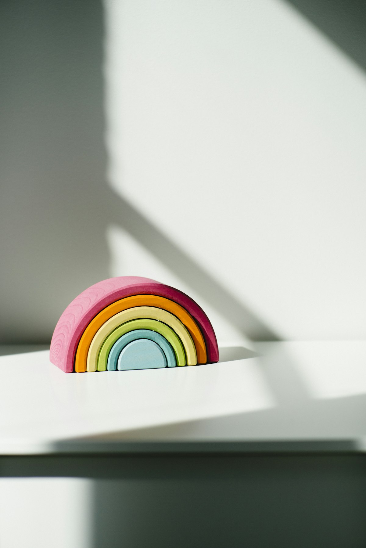 A pastel wooden rainbow stacker glowing in afternoon light