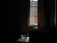 A compact air cooler sitting on a wooden table beside a sunny window.