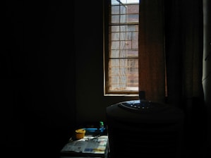 A sleek ivro air cooler placed in a bright, modern living room with sunlight streaming through large windows.