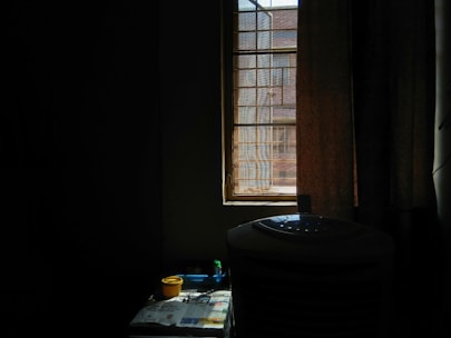 A sleek ivro air cooler placed in a bright, modern living room with sunlight streaming through large windows.