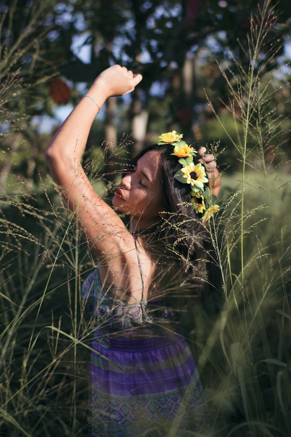 a woman standing in tall grass with a flower in her hair