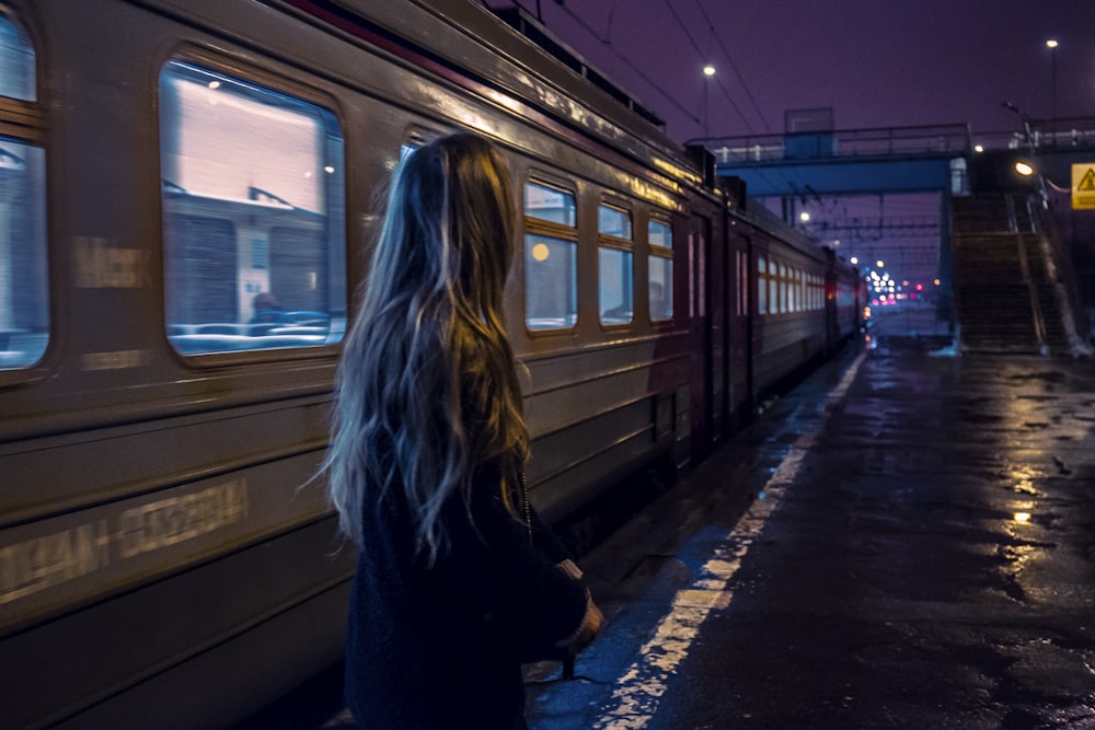 mulher em pé ao lado do trem cinza