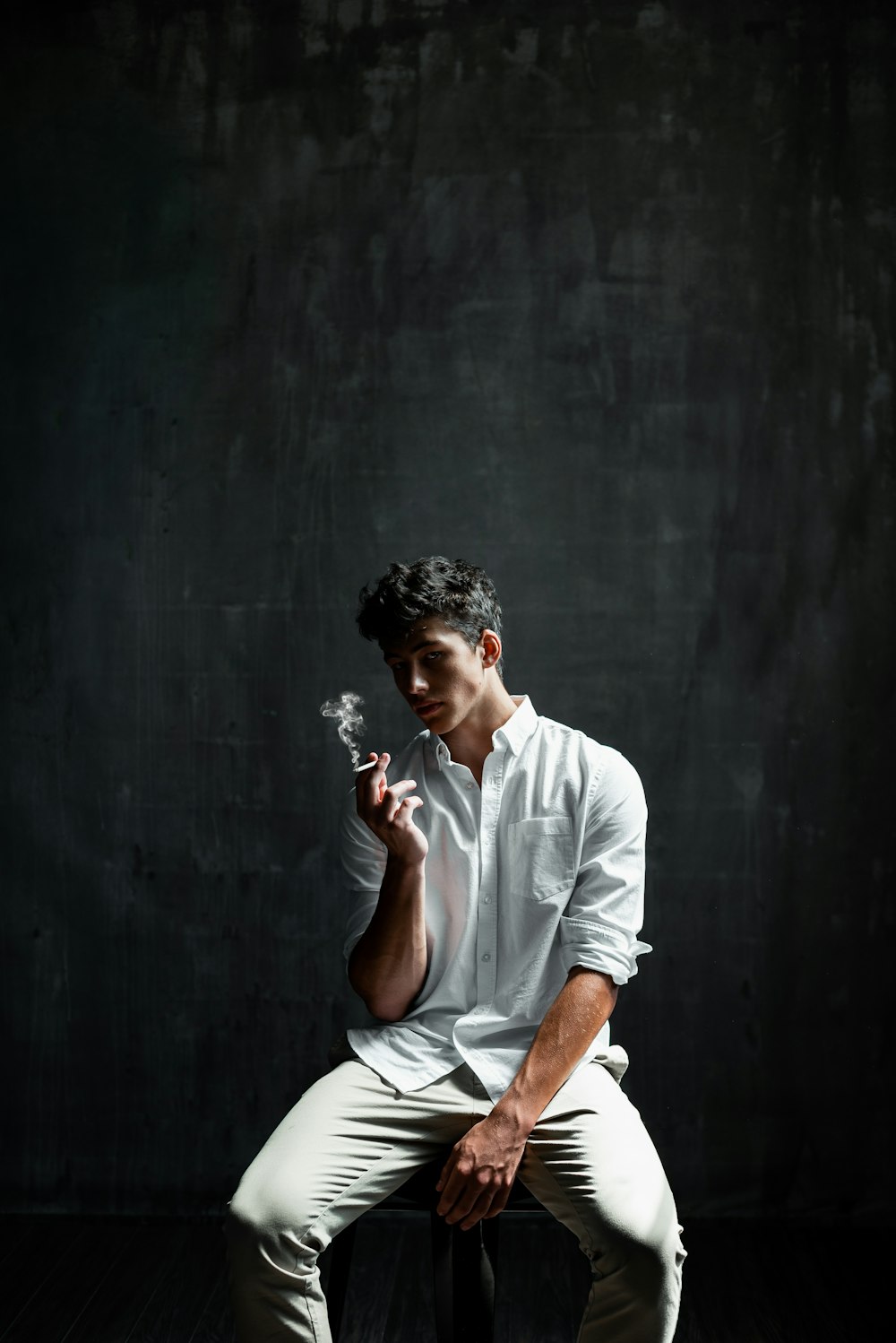 Mann sitzt auf Stuhl und raucht Zigarre