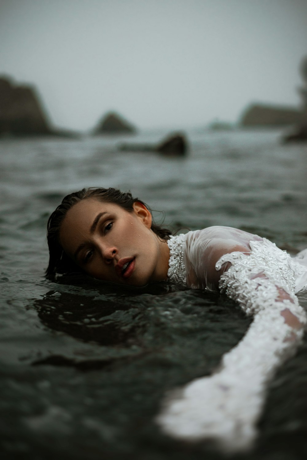 a woman laying on top of a body of water