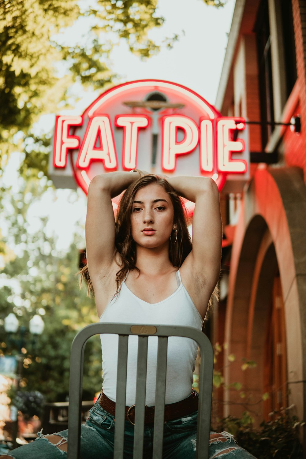 woman sitting on chair raising two arms near fat pie store