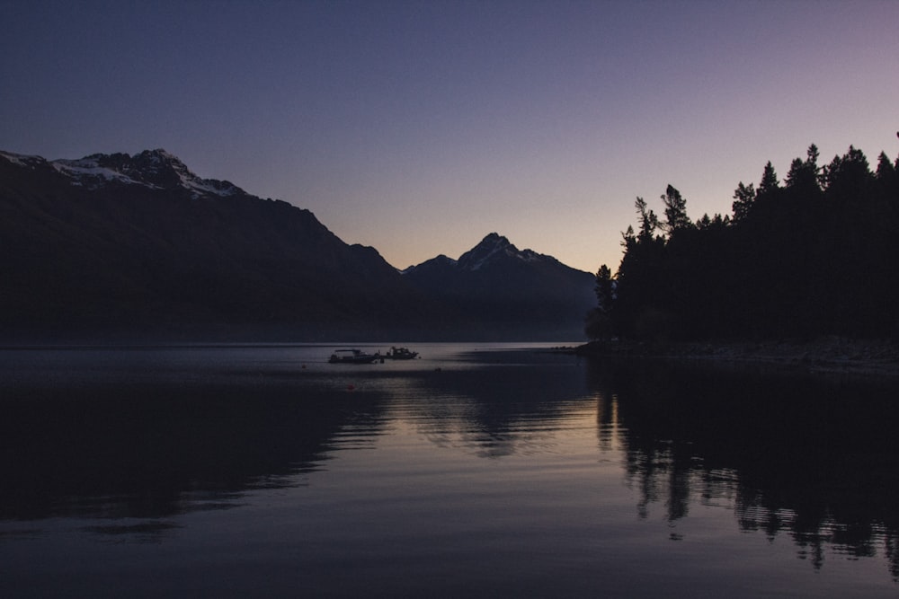 silhouette of body of water surrounded with mountains