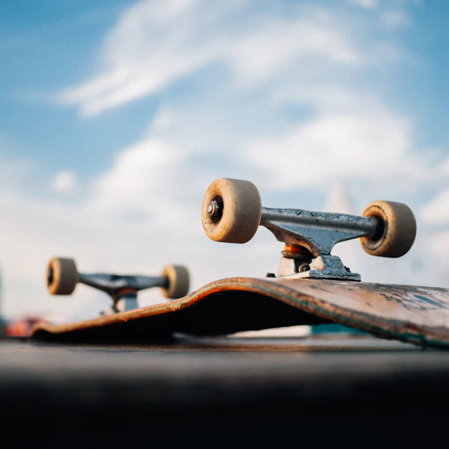 A brown wooden skateboard deck lying on the ground seen from above